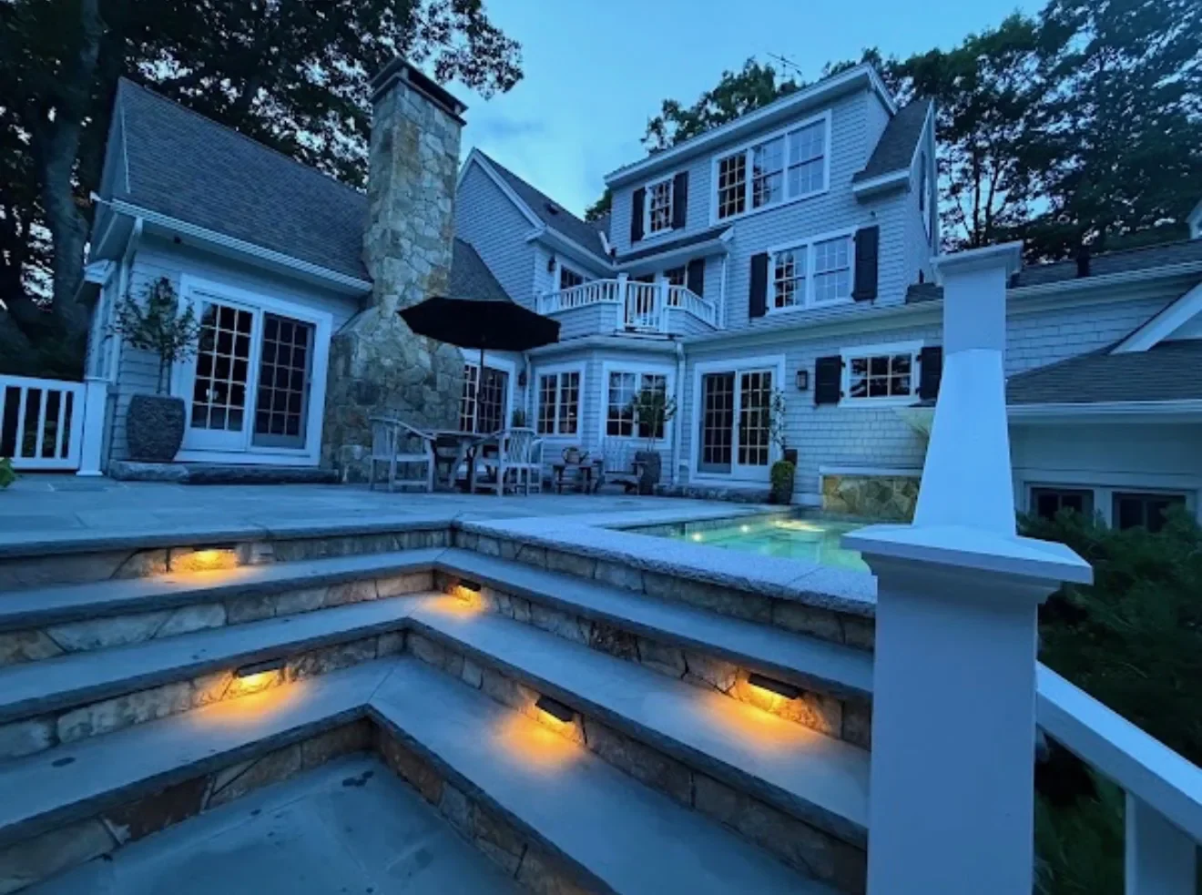 A Maine home at dusk with a lit pool and freshly cleaned windows