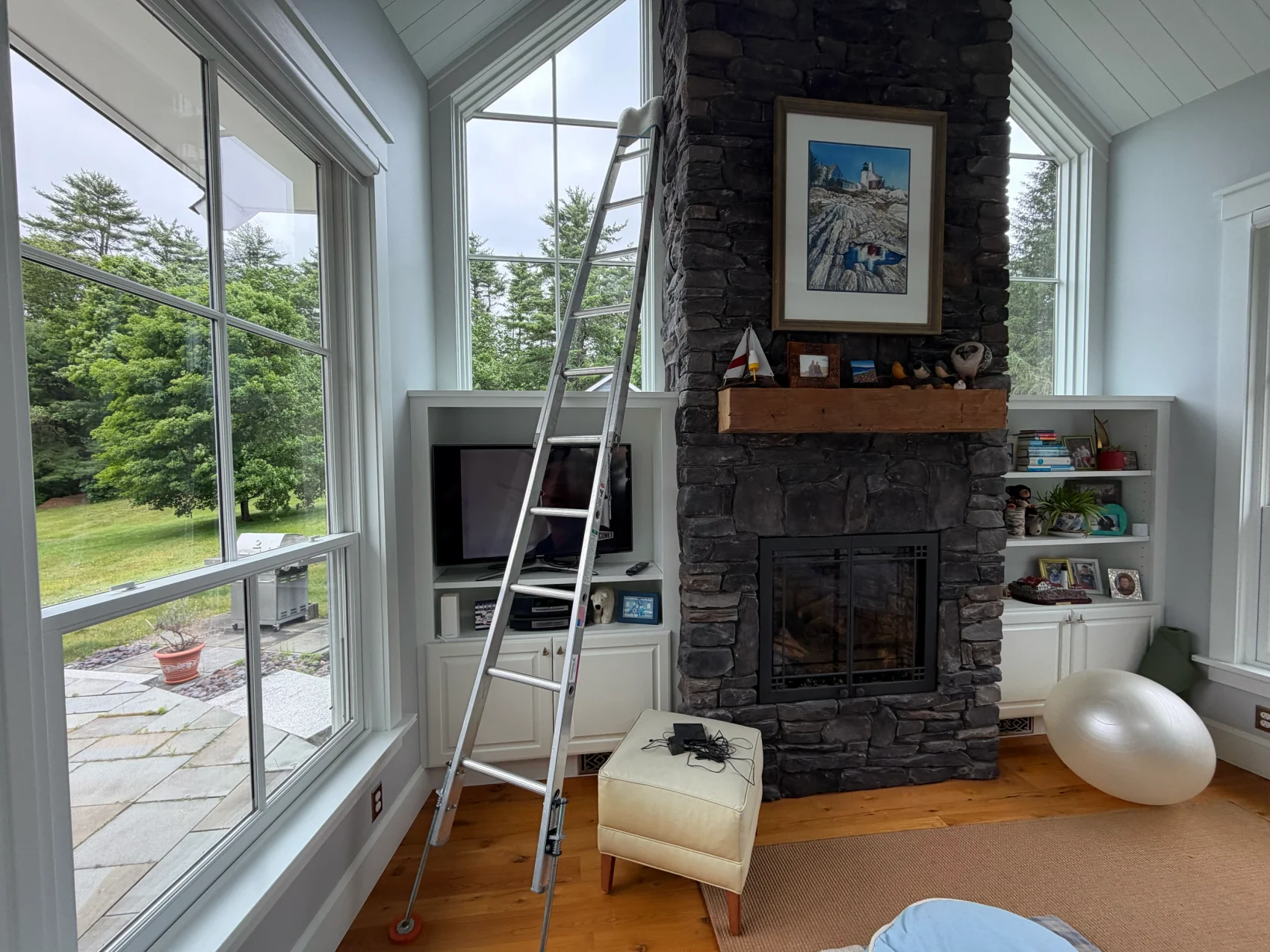 A ladder set up inside a great room with vaulted gable windows