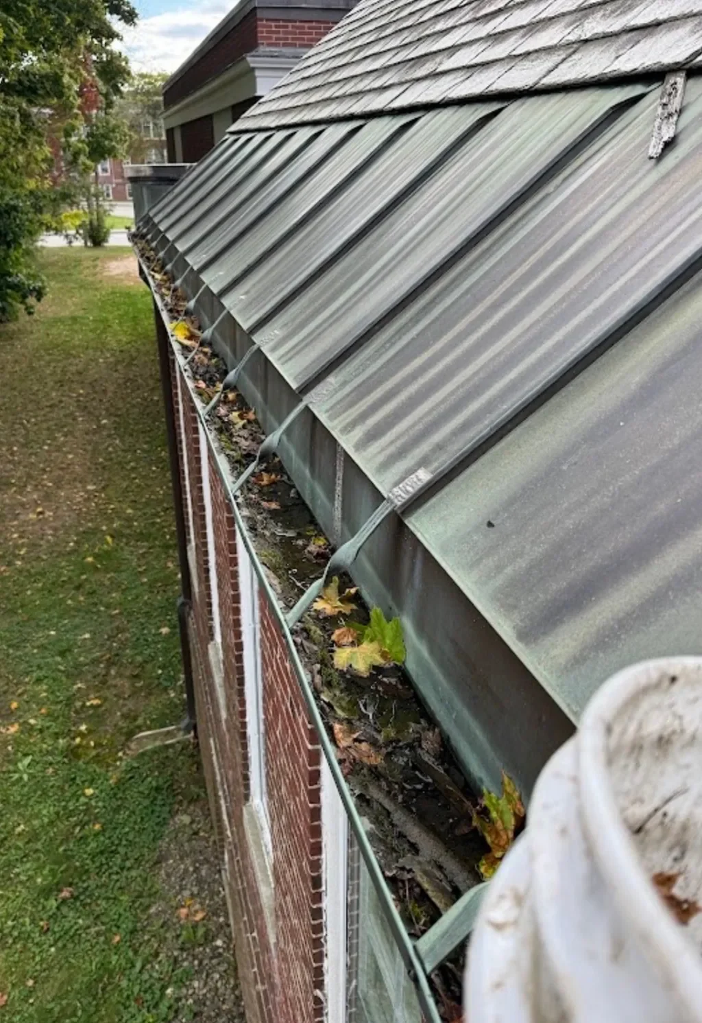 A long gutter run choked with leaves and silt before cleaning