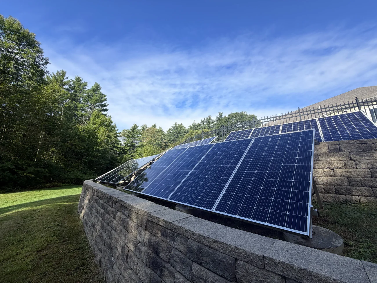 A ground-mounted solar array on a granite retaining wall, cleaned panel by panel